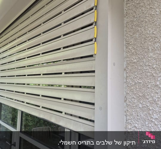 תריסים מותקנים על חלון חיצוני עם ידיות צהובות